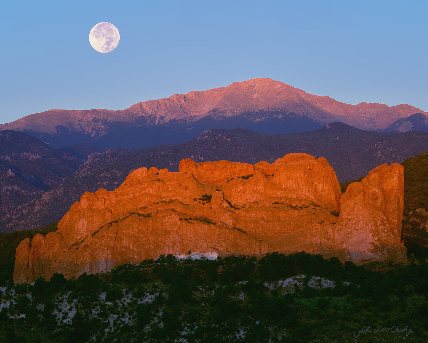 The full supermoon sets behind Pikes Peak and the cliffs of Garden of the Gods. I love how the rising sun makes the cliffs glow in this fine art landscape print!