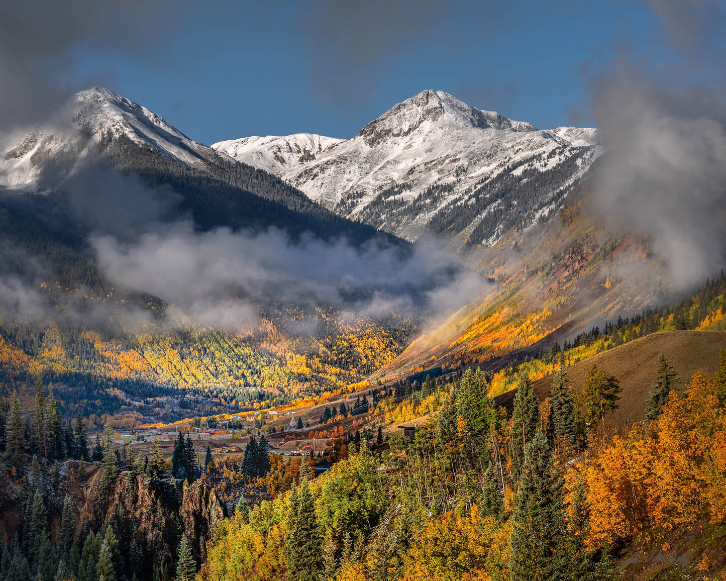 Low clouds dance with the sun and fall colors overlooking Silverton Colorado, nestled in its valley amid the San Juan Mountains. Fine Art Landscape Photography by McClusky Nature Photography