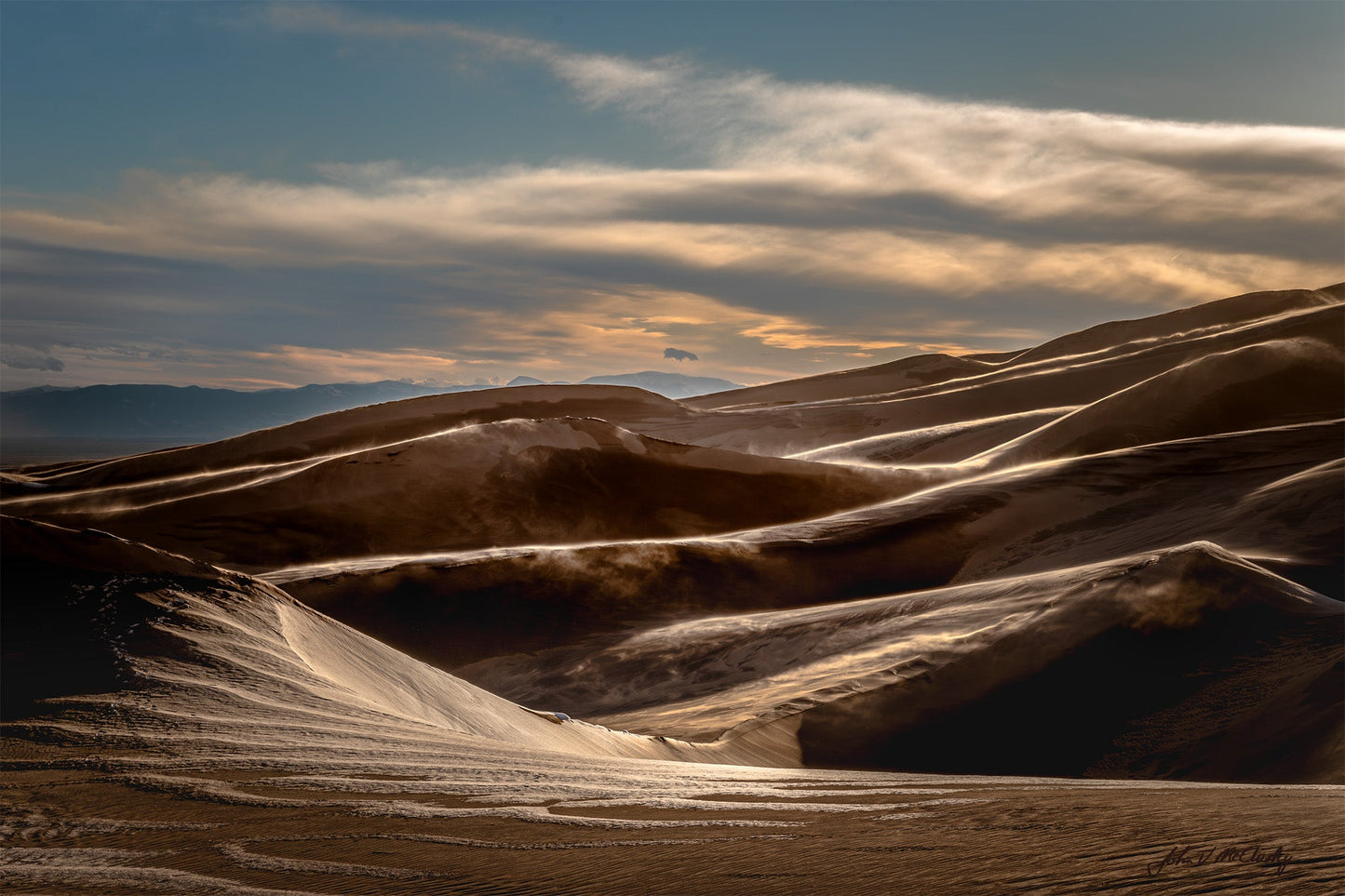 Wild winds at sunset blow sand and snow across the dunes at Great Sand Dunes National Park. Fine Art Landscape Photography by McClusky Nature Photography.