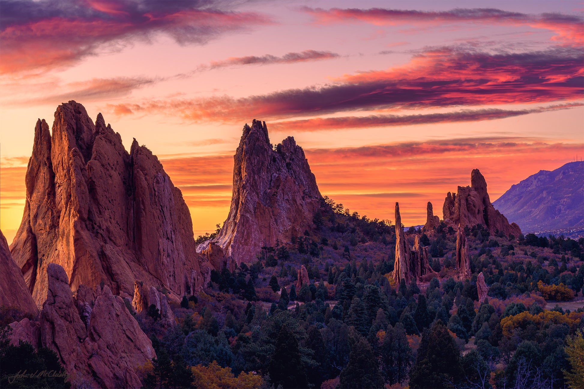 The standing outcrops at the Garden of the Gods glow in the breaking sunlight as the sky glows reds, pinks, and oranges.  Fine Art landscape photography print by McClusky Nature Photography.