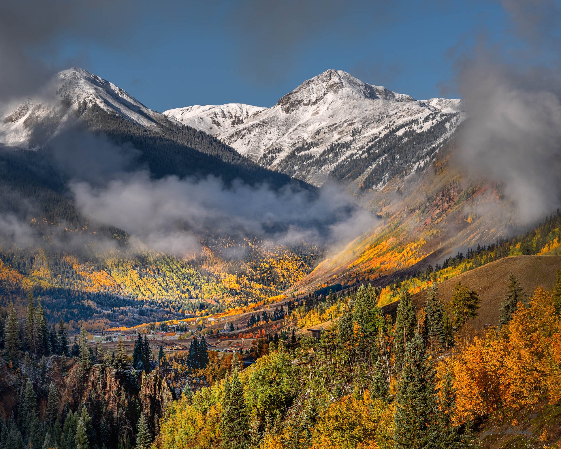 Low clouds dance with the sun and fall colors overlooking Silverton Colorado, nestled in its valley amid the San Juan Mountains.  Fine Art Landscape Photography by McClusky Nature Photography