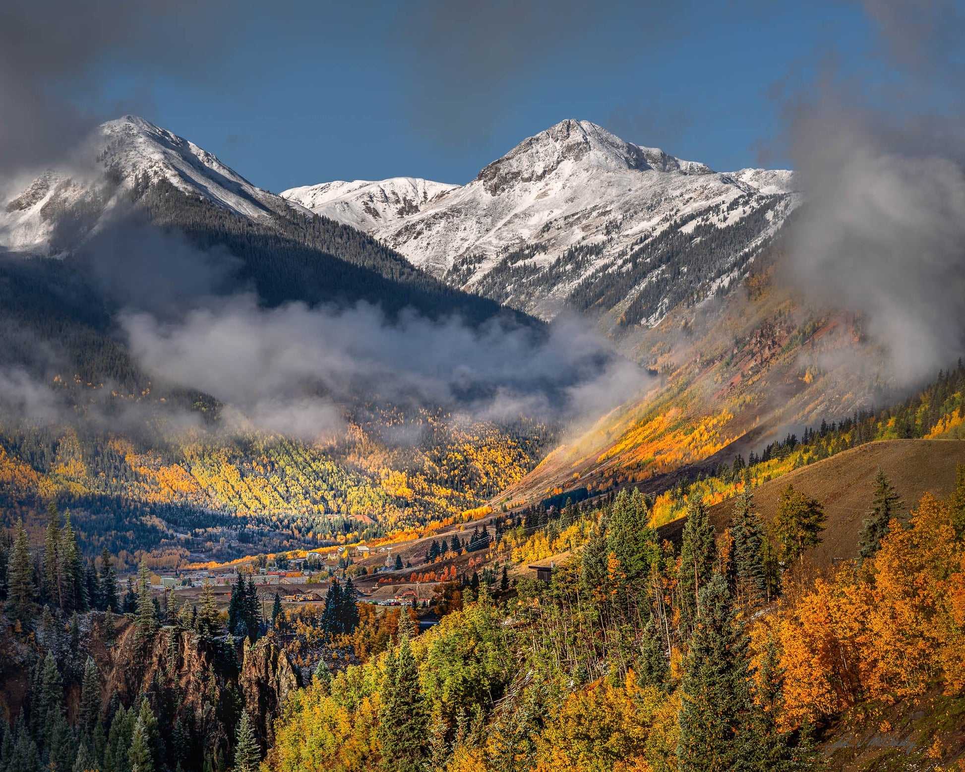 Low clouds dance with the sun and fall colors overlooking Silverton Colorado, nestled in its valley amid the San Juan Mountains.  Fine Art Landscape Photography by McClusky Nature Photography