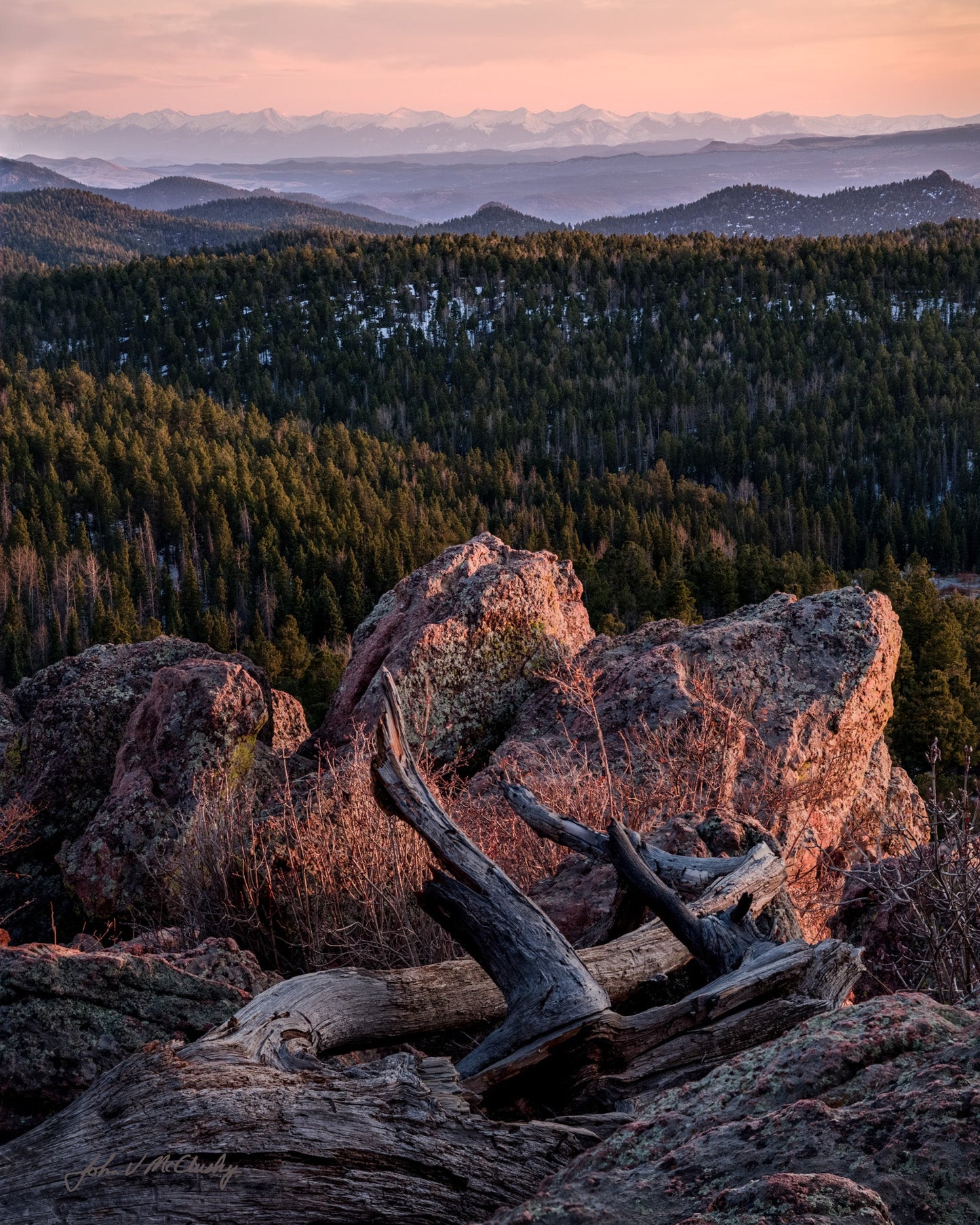 Scenic view of a forested landscape with mountains at sunset.
