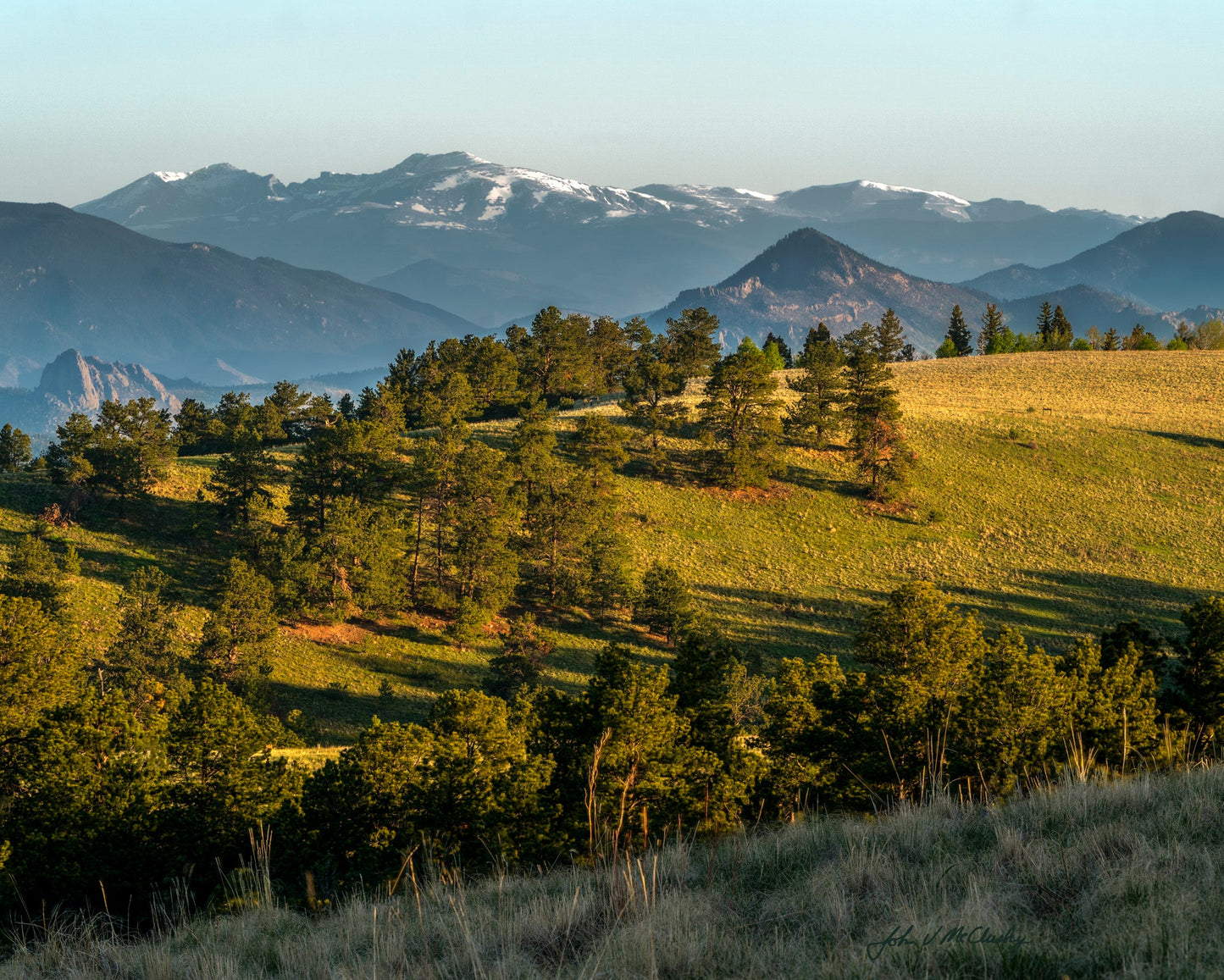 Scenic view of mountains with snow-capped peaks and a valley with trees and fields.