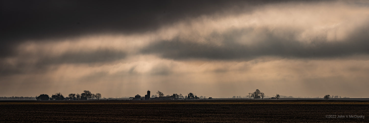 Dramatic clouds and god rays overlook distant homesteads on the Illinois plains.  Landscape  photography Print by McClusky Nature Photography.
